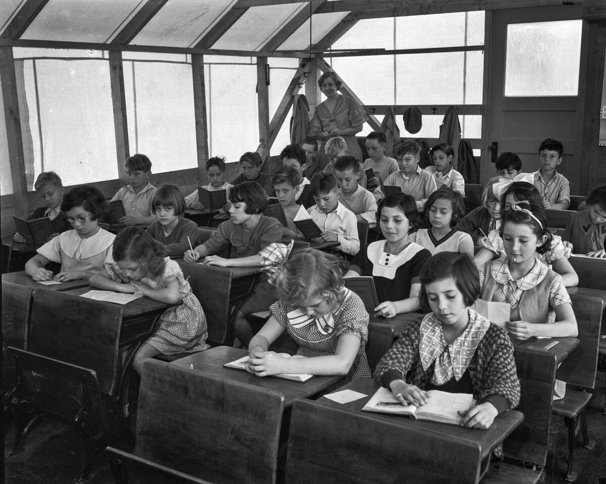 March 1934: Children diligently read while their teacher watches from the back of their makeshift classroom at La Cienega School.