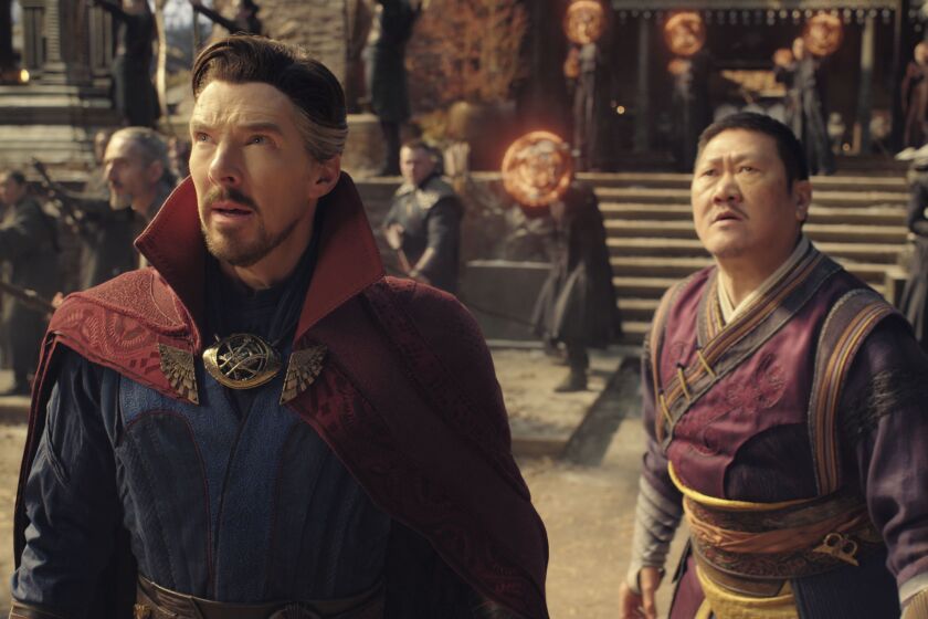 A man in a rep cape looking up at the sky and a man in a purple costume looking up at the sky