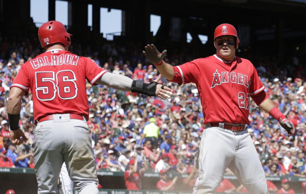 Angels outfielder Kole Calhoun (56) and Mike Trout (27) celebrate after scoring on a single by C.J. Cron during a game against the Rangers on May 1.