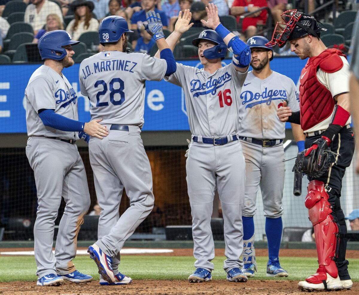 Dodgers designated hitter J.D. Martinez is congratulated at home plate by teammates Max Muncy, Will Smith and David Peralta.
