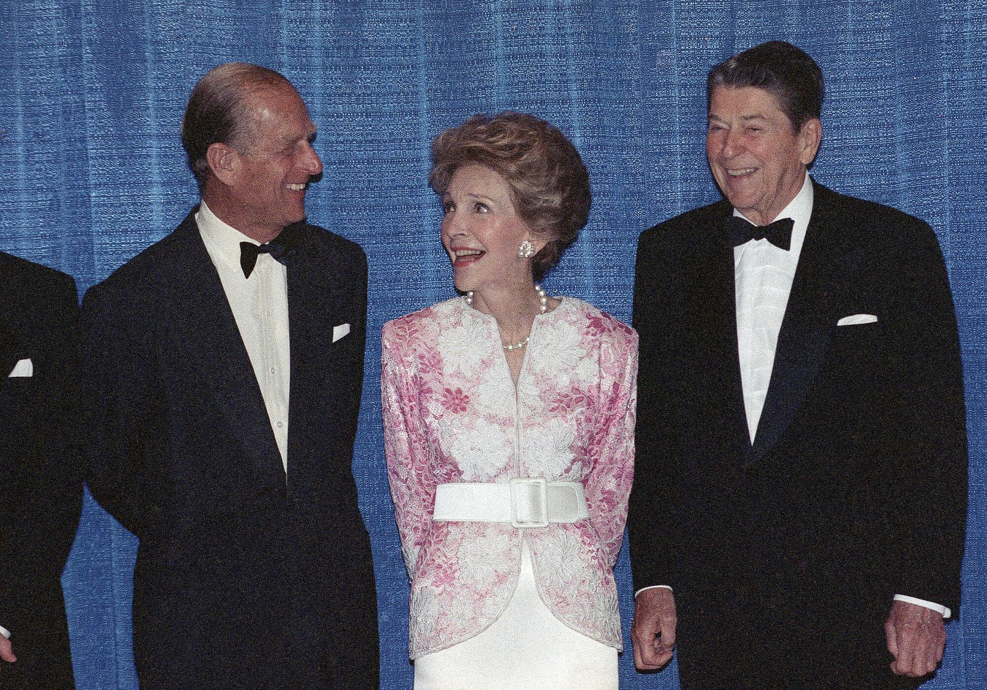 Prince Philip, Nancy Reagan and former President Reagan laugh as they stand in a formal line.