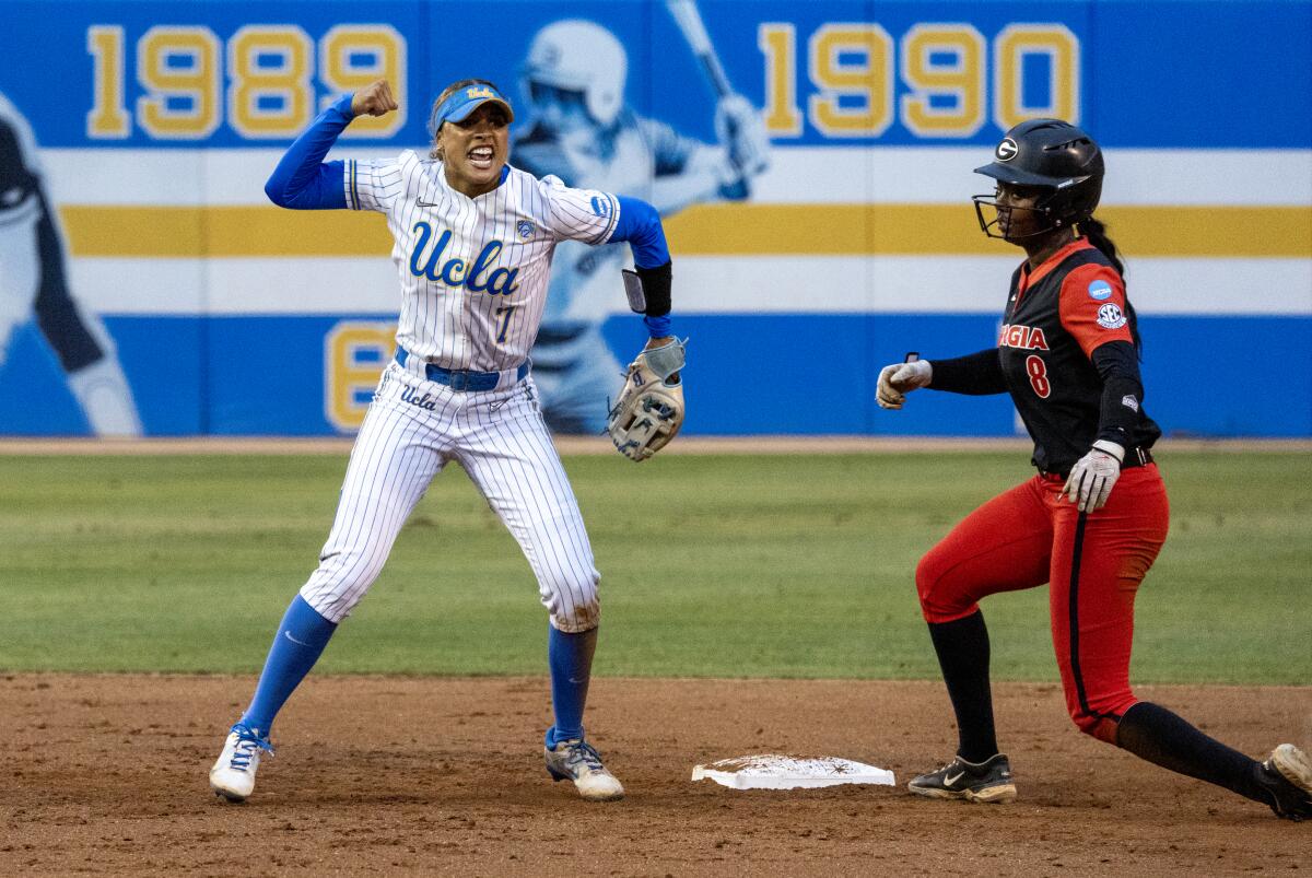 UCLA shortstop Maya Brady raises her fist after completing a double play in front of Georgia's Jayda Kearney.