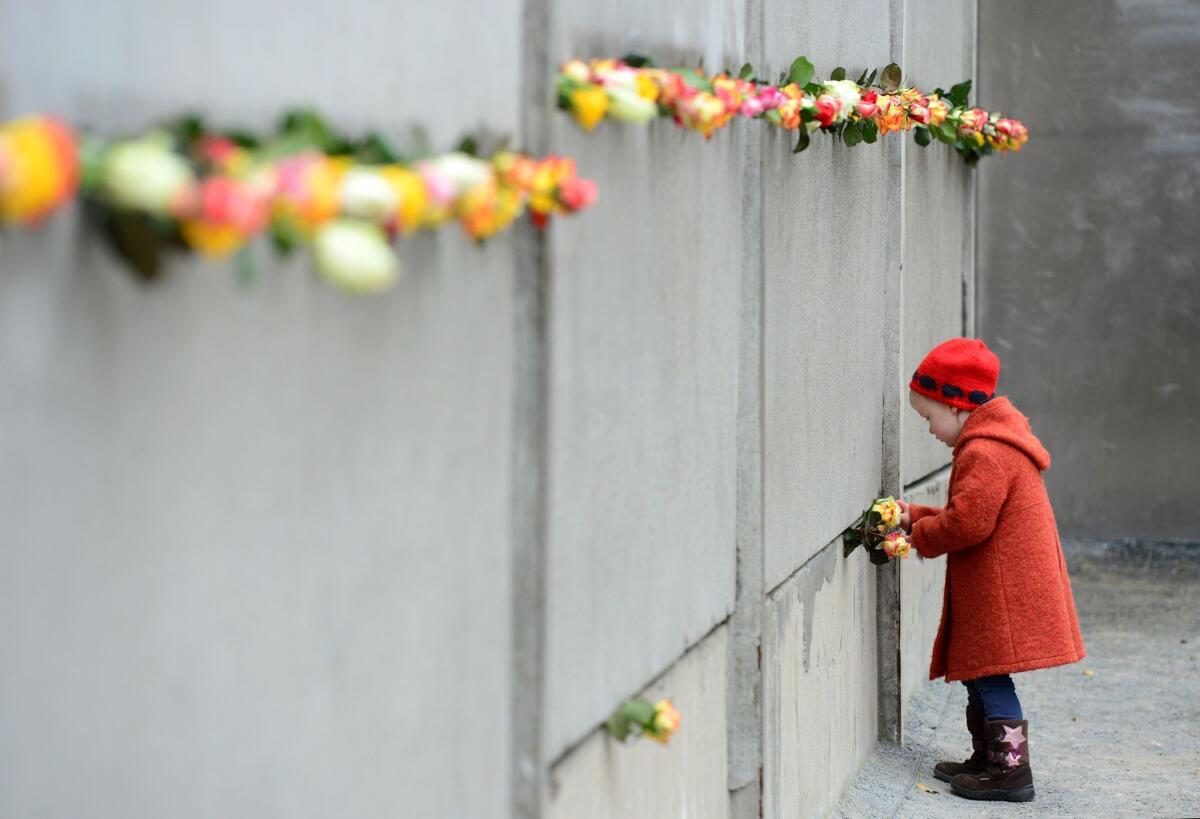 A young girl slips a rose in a preserved segment of the Berlin Wall during the commemorations to mark the 25th anniversary of the fall of the Berlin Wall at the Berlin Wall Memorial in the Bernauer Strasse in Berlin.