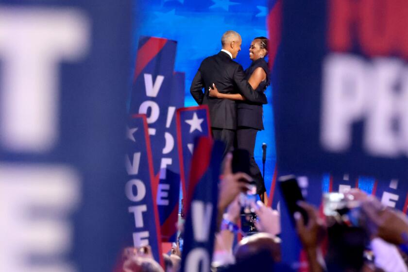 DNC CHICAGO, IL AUGUST 20, 2024 - Former President Barack Obama, left, embraces his wife former first lady Michelle Obama on stage during the 2024 Democratic National Convention at United Center in Chicago on Tuesday, August 20, 2024 in Chicago, IL. (Myung J. Chun/Los Angeles Times)