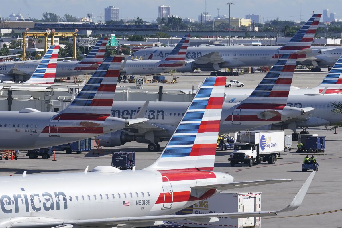 FILE - American Airlines planes are parked at Miami International Airport gates, on Nov. 23, 2021, in Miami. American Airlines is joining rivals in predicting a boom in revenue this summer, as people crowd on planes after two years of pandemic. American said Friday that second-quarter revenue will rise 11% to 13% above the same quarter in 2019. That's even rosier than American's previous forecast. (AP Photo/Marta Lavandier, File)