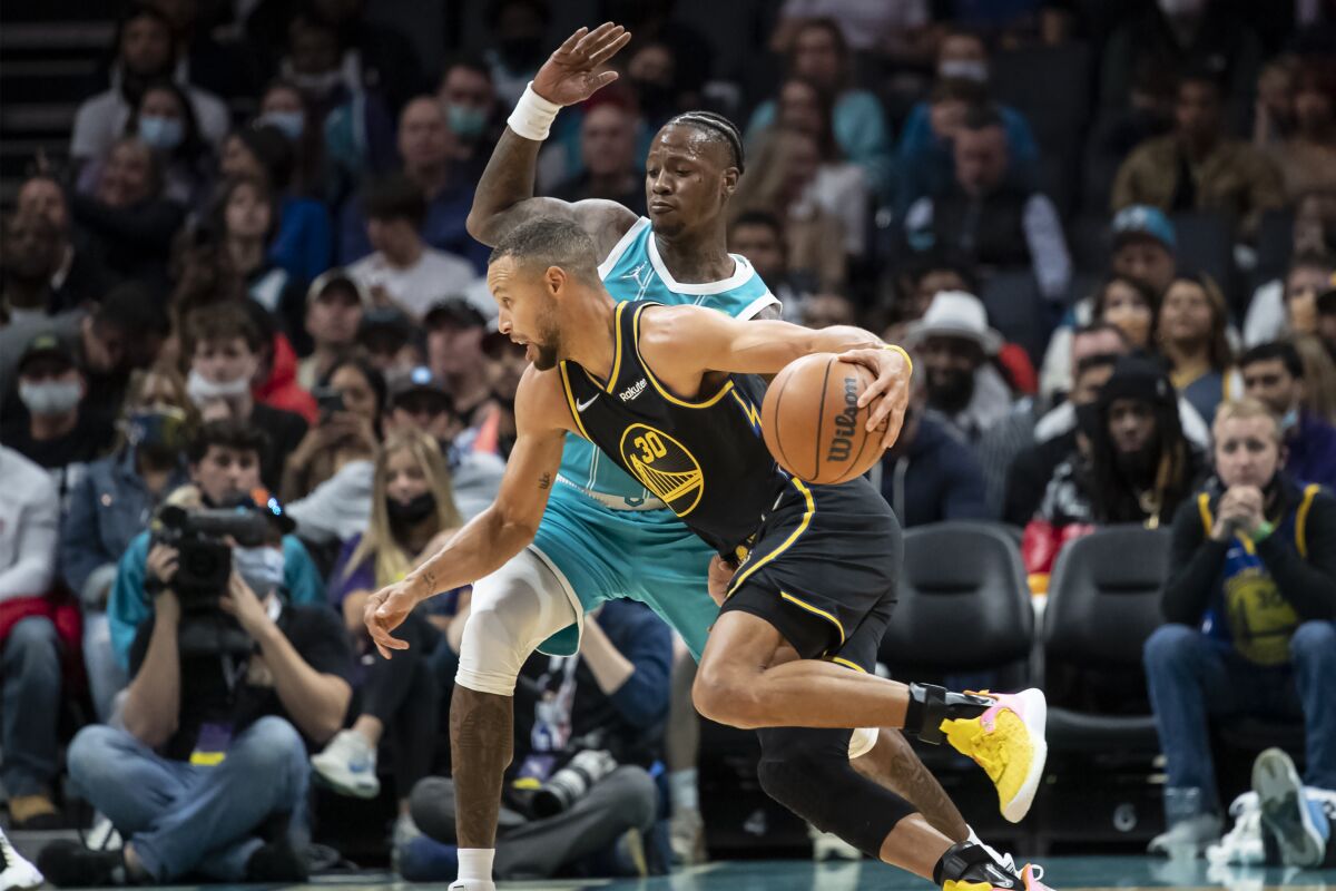 Charlotte Hornets guard Terry Rozier, top, defends against Golden State Warriors guard Stephen Curry (30) during the first half of an NBA basketball game, Sunday, Nov. 14, 2021, in Charlotte, N.C. (AP Photo/Matt Kelley)