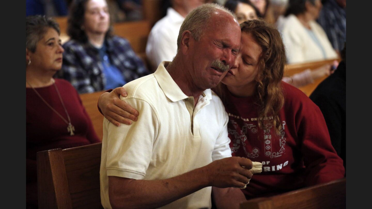Gianna Gathman, 18, hugs her grandfather Jim Schettler during Mass at St. Rose Church in Santa Rosa on Sunday. Gathman's family lost their home in the Fountaingrove neighborhood to the fire. They are now living with the Schettlers.