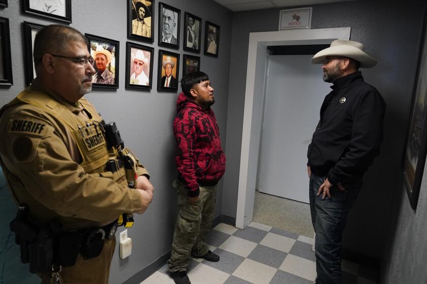 El jefe de policía del condado Terrell, Thaddeus Cleveland, habla con un migrante mexicano recientemente detenido, mientras el sargento Manuel Jimenez permanece a un costado, en el Departamento de Policía del condado Terrell, el jueves 21 de marzo de 2024, en Sanderson, Texas. (AP Foto/Erik Verduzco)