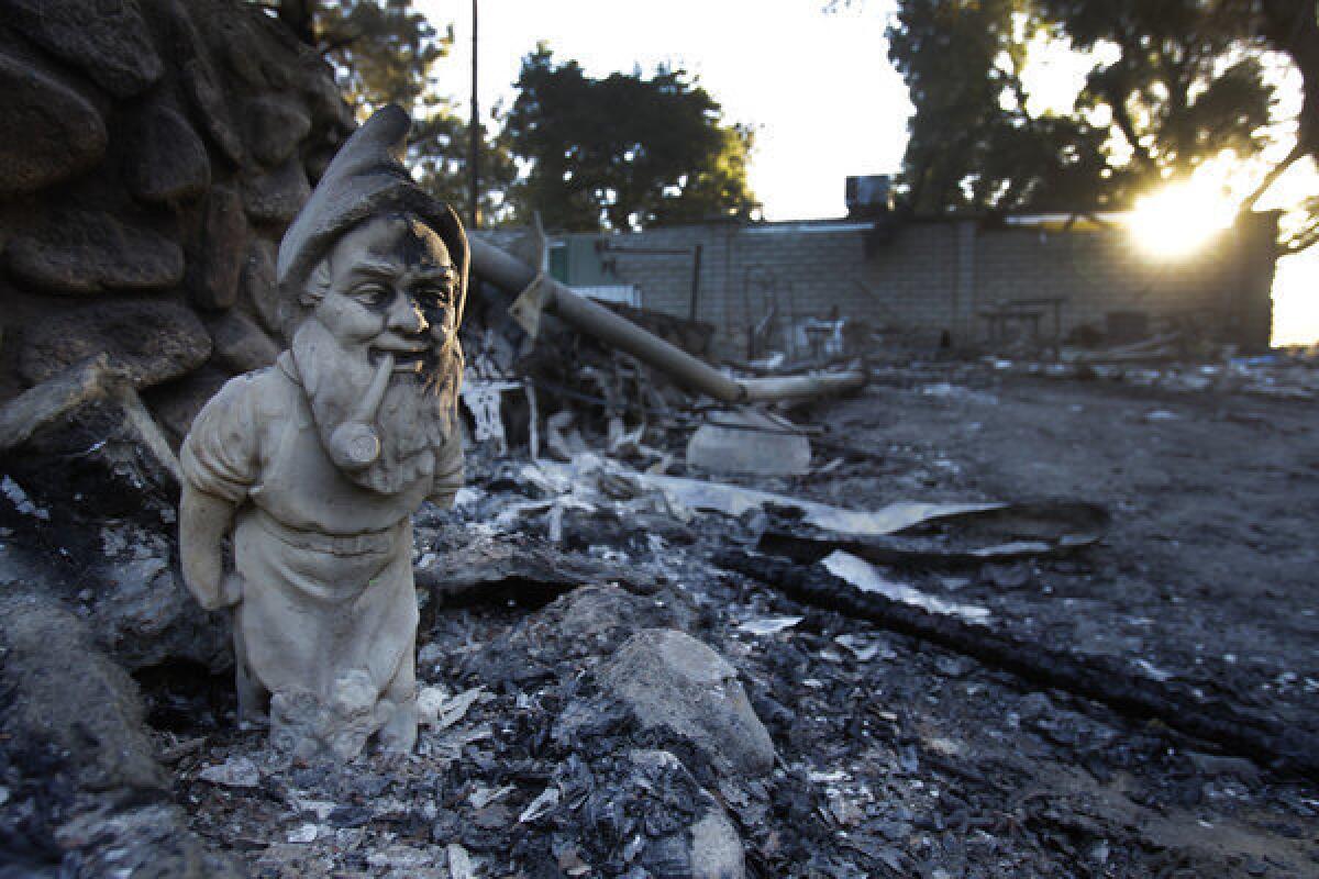 A yard gnome seems to stand sentry near a burned-out home in the Poppet Flats neighborhood after the Silver fire burned through.