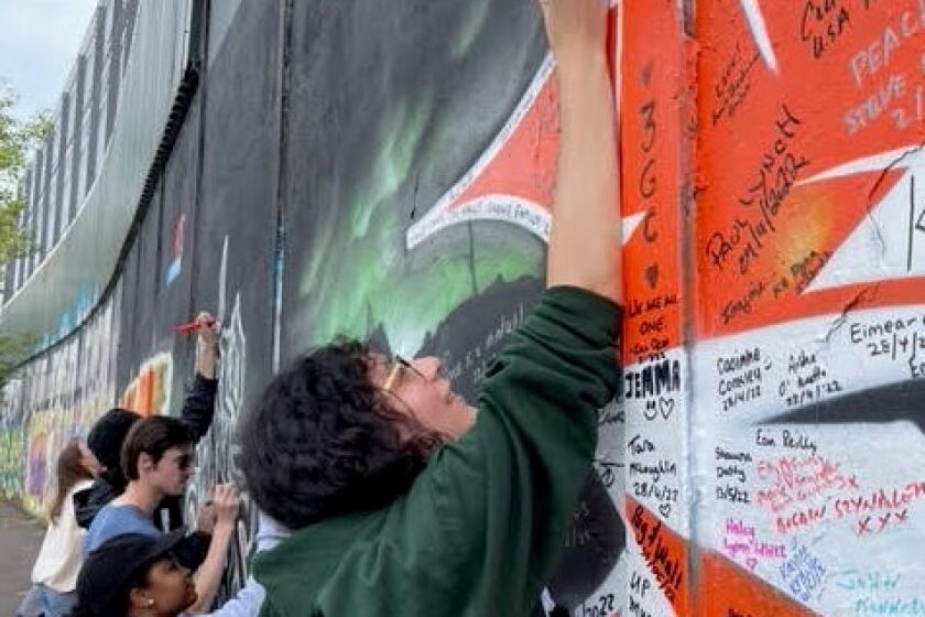 Possible Caption: San Diego State University students studying abroad in 2022 sign the Peace Wall in Belfast, Northern Ireland which separates a Catholic neighborhood from the Protestant dominated city.