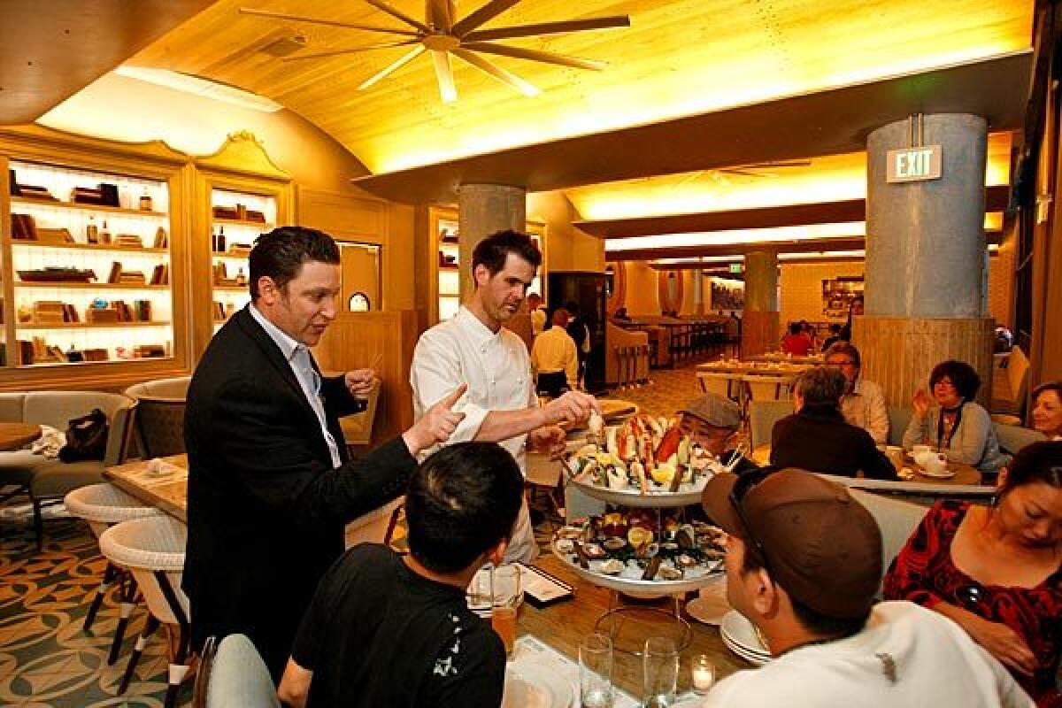 Brent Berkowitz, left, director of operations of the Innovative Dining Group, and chef Sascha Lyon show off le petit delphine -- a seafood platter -- to guests.