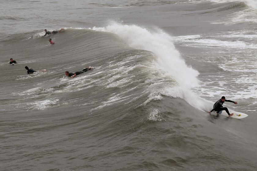 Surfers take advantage of waves spawned by Hurricane Arthur on Friday off Avalon, N.C.