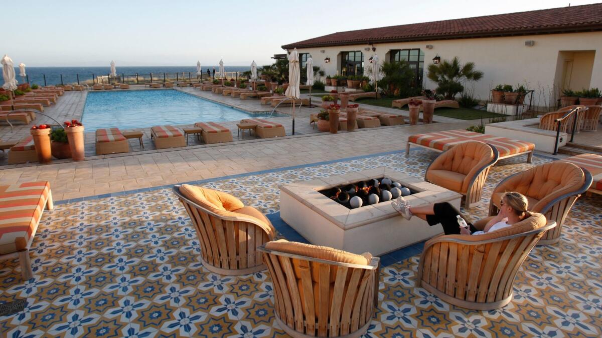 A woman relaxes by the fire pit overlooking the swimming pool and ocean at the Terranea resort in Rancho Palos Verdes. A proposed ordinance would require the hotel and a nearby golf club to provide "panic buttons" to address sexual assaults and other emergencies.