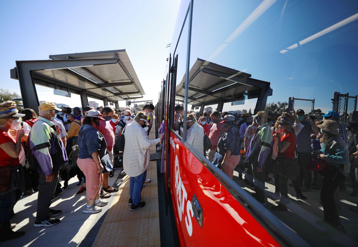 People board the Mid-Coast Extension of the UC San Diego Blue Line Trolley during a grand opening celebration on Sunday.