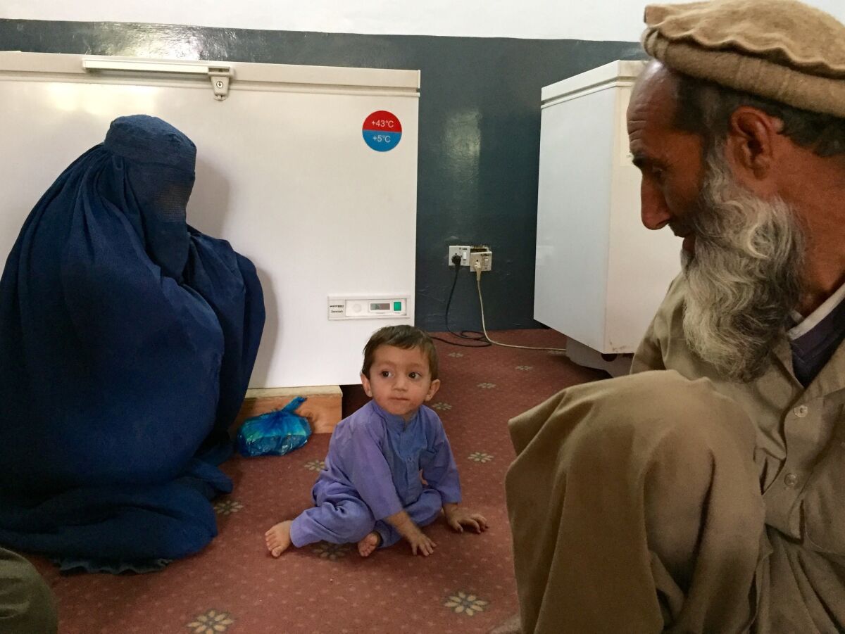 Khaksar is watched by his grandfather, Duran, at right, and his mother before an appointment with doctors in Asadabad, Afghanistan.
