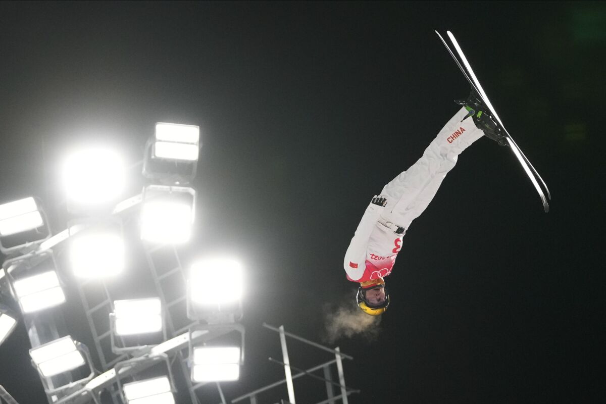 China's Jia Zongyang soars upside down near the lights during the men's aerials finals.