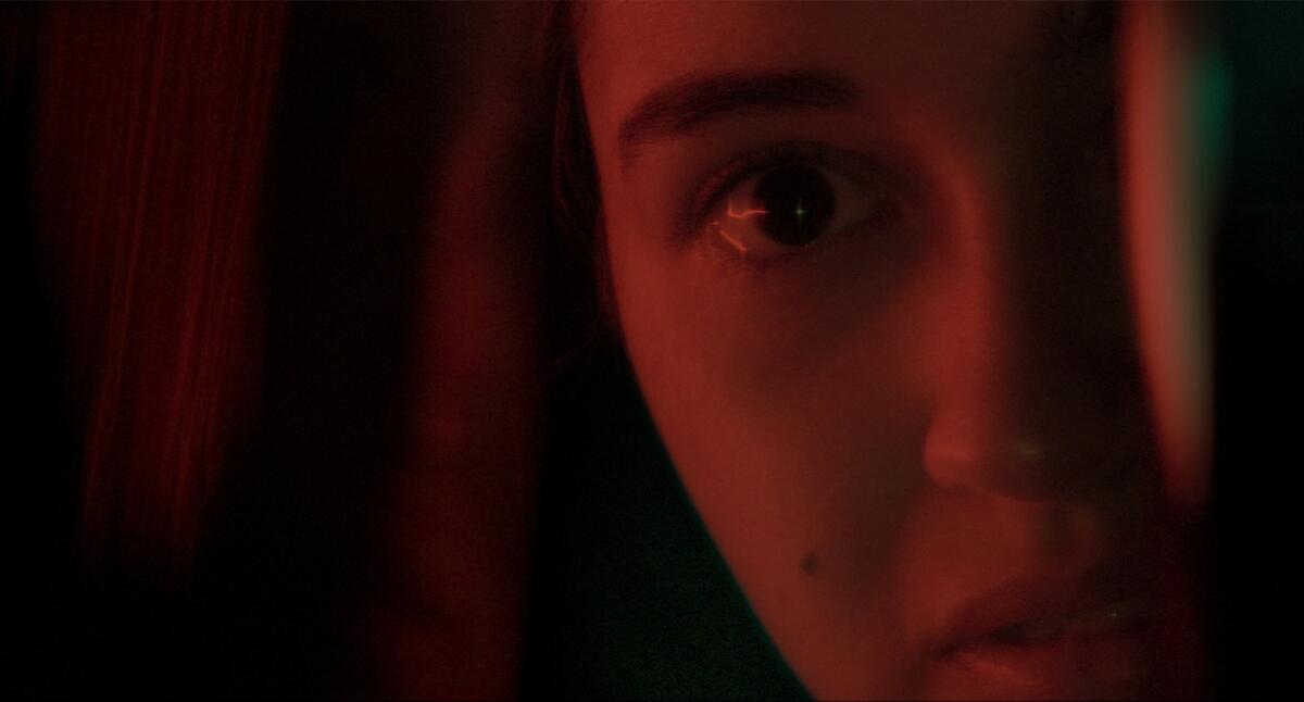 A close up of the face of a girl bathed in dark red light.