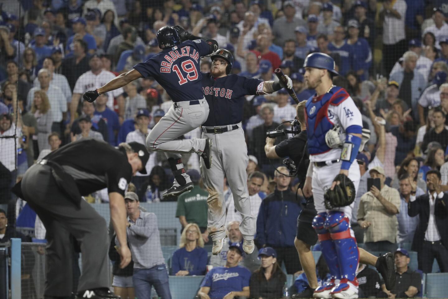 While Dodgers Yasmandi Grandal waits, Red Sox's Christiian Vasquez, right celebrates Jackie Bradley Jr.’s eighth inning homer, tying the game at one.