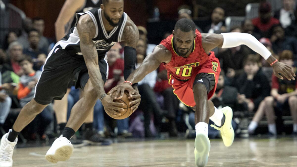 Spurs guard Jonathon Simmons, left, and Hawks guard Tim Hardaway Jr. (10) vie for a loose ball during the second half Sunday.