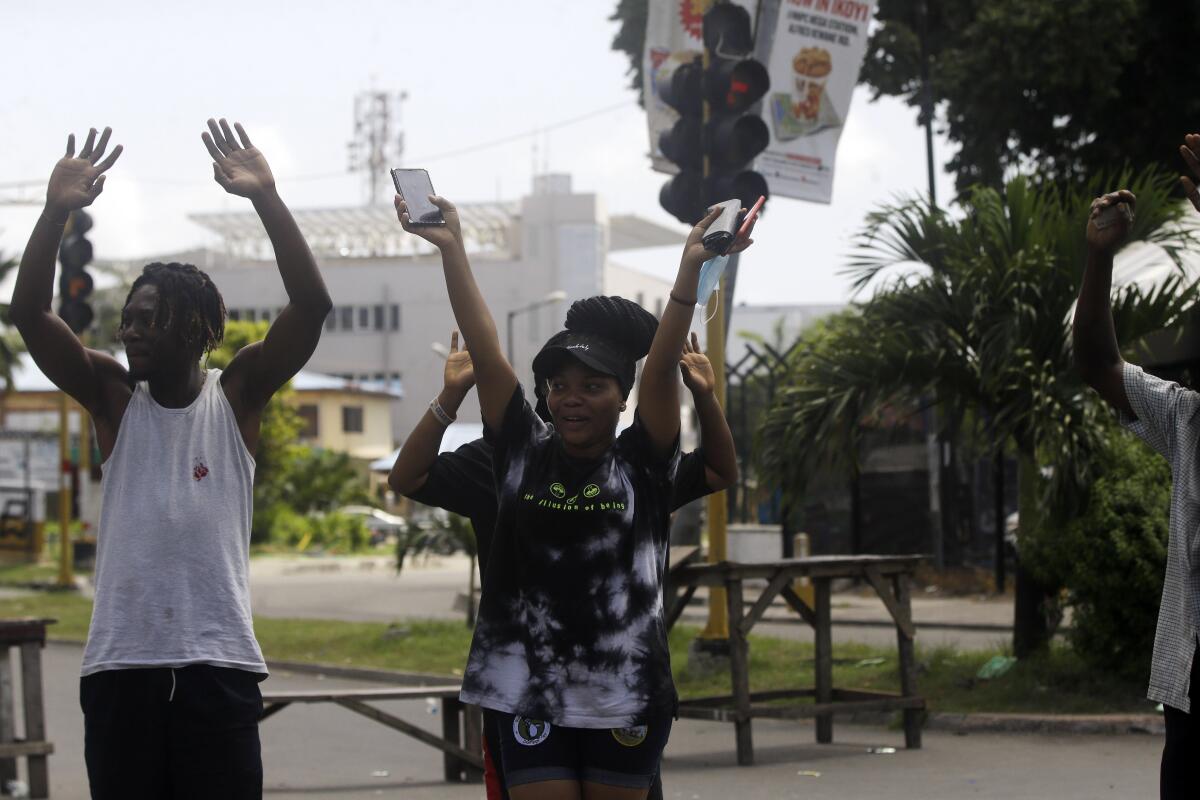 People raise their hands as they approach a police checkpoint in Lagos, Nigeria.