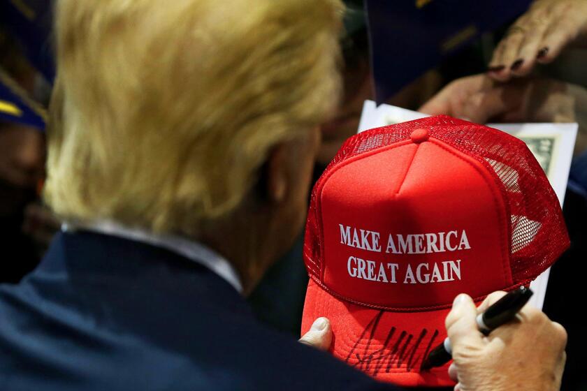Donald Trump signs one of his iconic campaign hats during an event in Iowa in January.