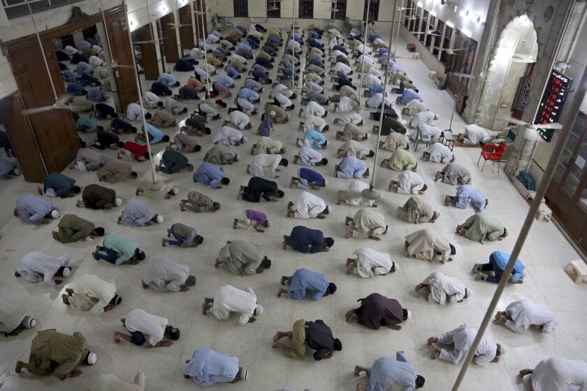 FILE - In this Sunday, April 19, 2020, file photo, people attend evening prayers while maintaining a level of social distancing to help avoid the spread of the coronavirus, at a mosque in Karachi, Pakistan. As Ramadan begins with the new moon later this week, Muslims all around the world are trying to work out how to maintain the many cherished rituals of Islam’s holiest month. (AP Photo/Fareed Khan, File)