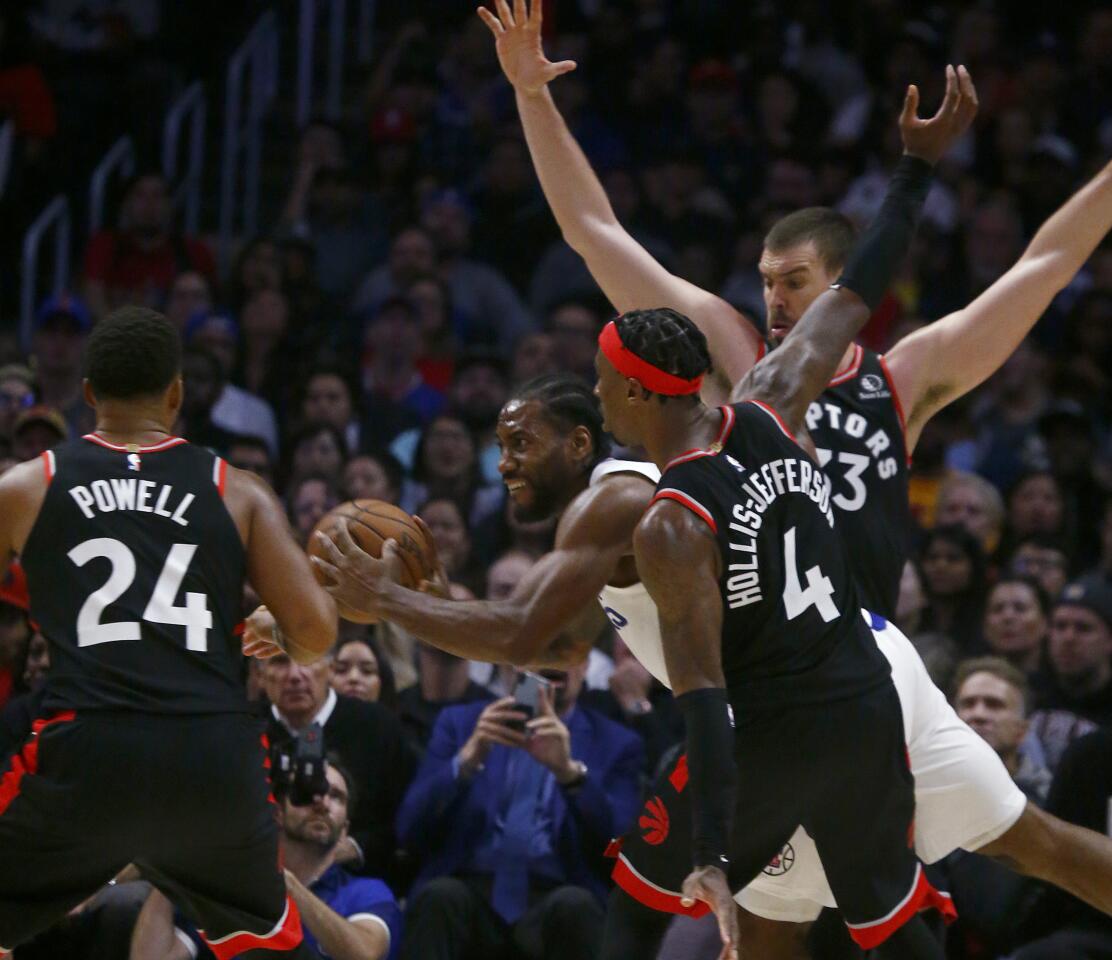 Clippers forward Kawhi Leonard tries to cut through a trio of Raptors defenders during the third quarter of a game Nov. 11 at Staples Center.