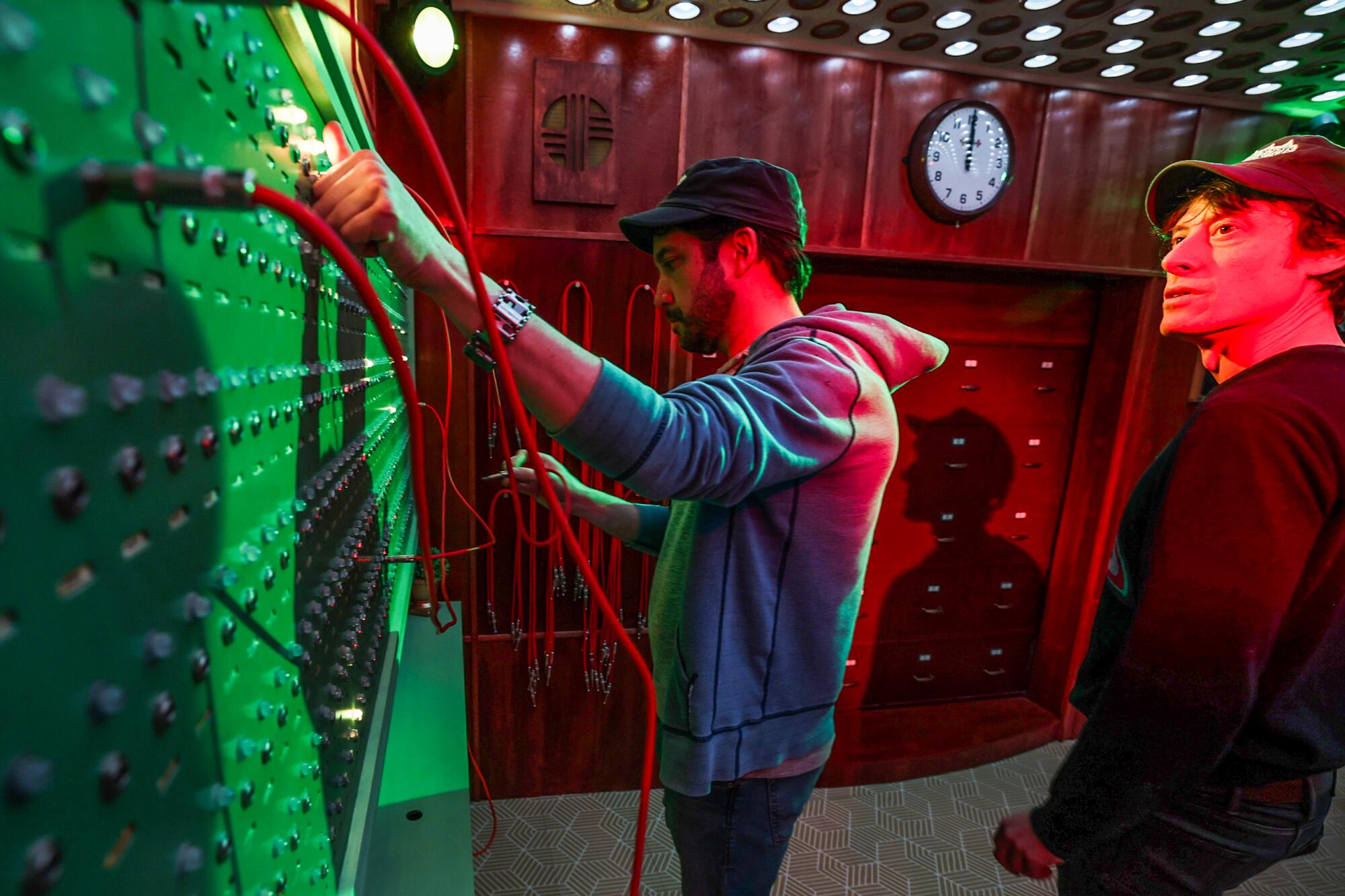 Tommy Wallach, right, and Terry Pettigrew-Rolapp, left, putting plugs into a switchboard in an escape room.