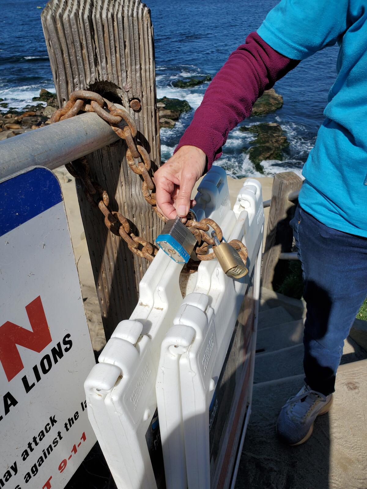Robyn Davidoff shows a silver lock placed on signs that instruct people to keep their distance from sea lions in La Jolla.