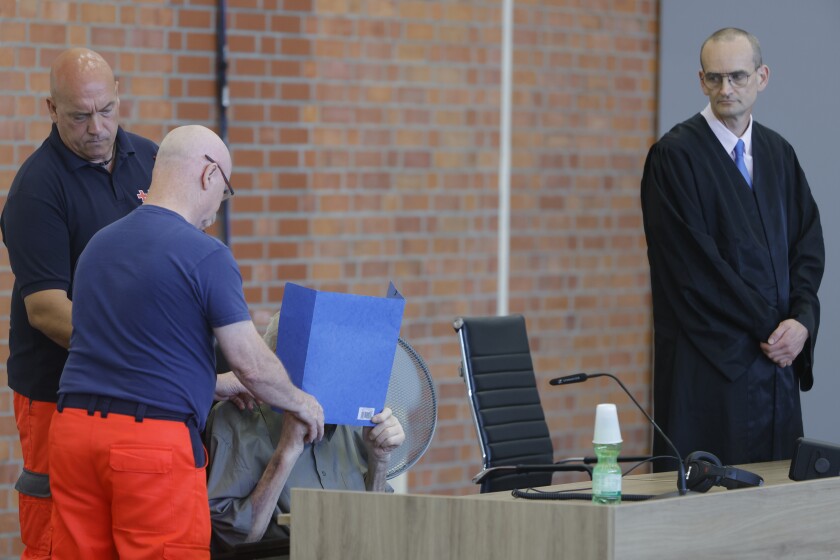 The accused Josef S. covers his face as he sits at the court room in Brandenburg, Germany, Tuesday, June 28, 2022. A 101-year-old man has been convicted of 3,518 counts of accessory to murder for serving at the Nazis' Sachsenhausen concentration camp during World War II. The Neuruppin Regional Court sentenced him to five years in prison on Tuesday. (AP Photo/Michele Tantussi)