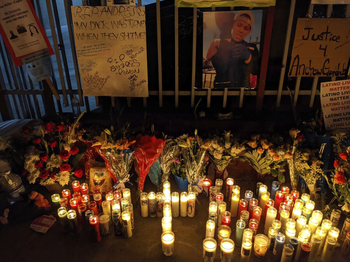 Dozens of candles at a makeshift memorial at a fence.