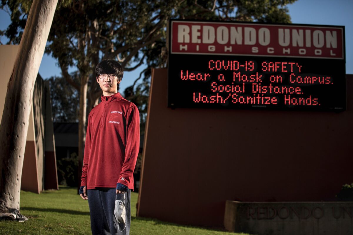 Michael Lee-Chang,18, a senior at Redondo Union High School, in front of the school’s sign along Pacific Coast Highway