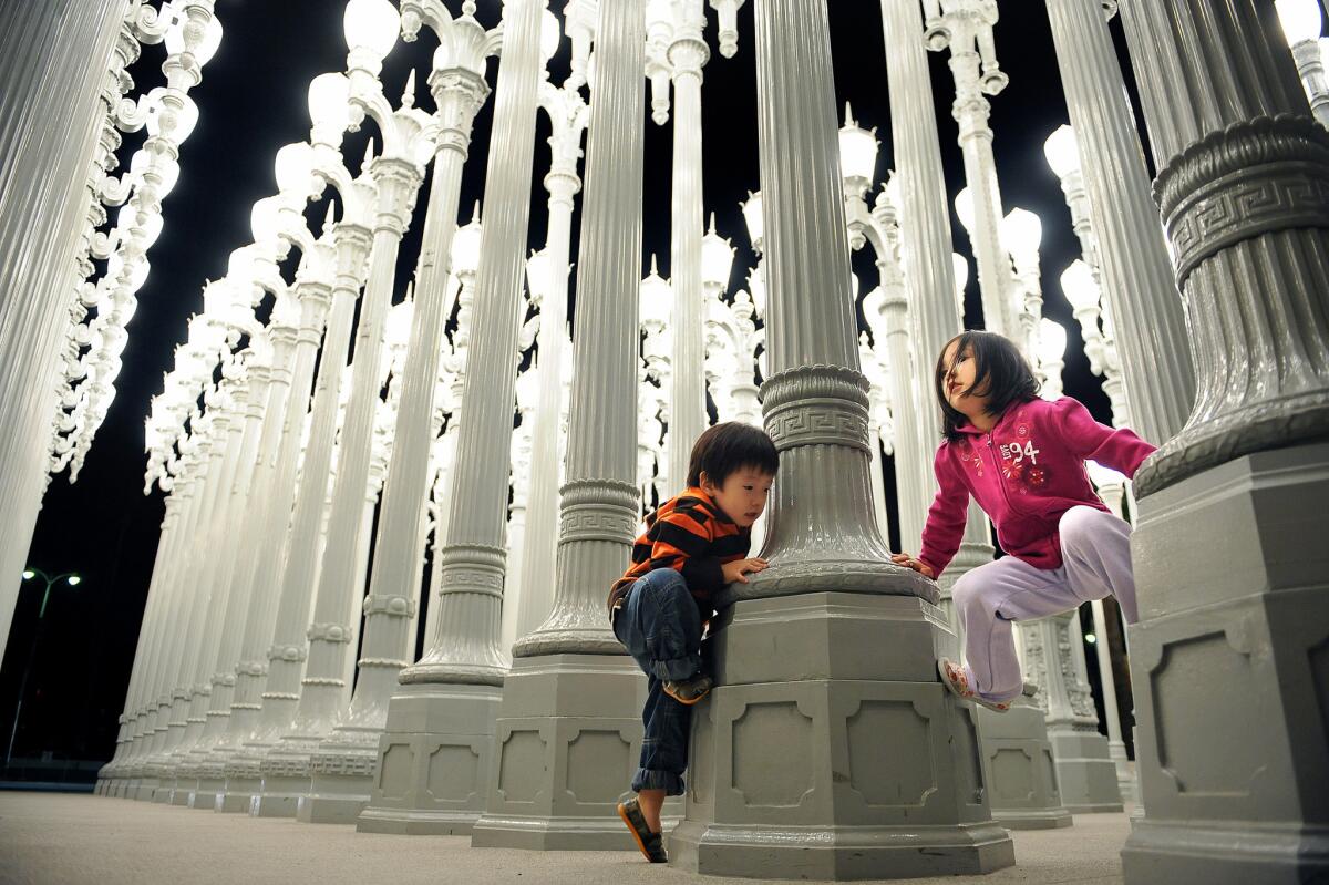 Brayden Yu, 2, and his sister Irene, 4, climb the "Urban Light " sculpture at LACMA on Wilshire Boulevard in October 2011.