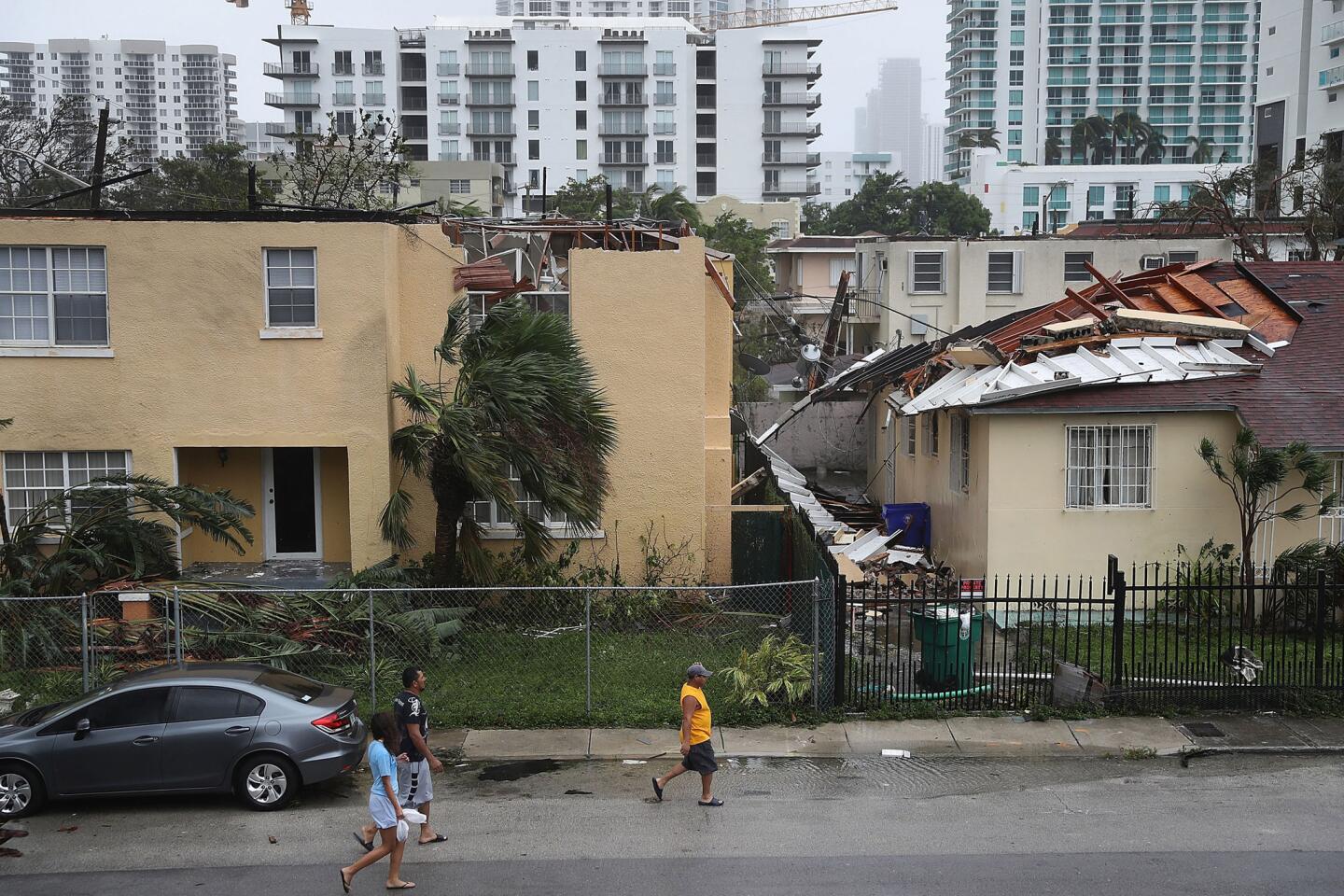 People walk past a building where the roof was blown off by Hurricane Irma on Sept. 10, 2017 in Miami.
