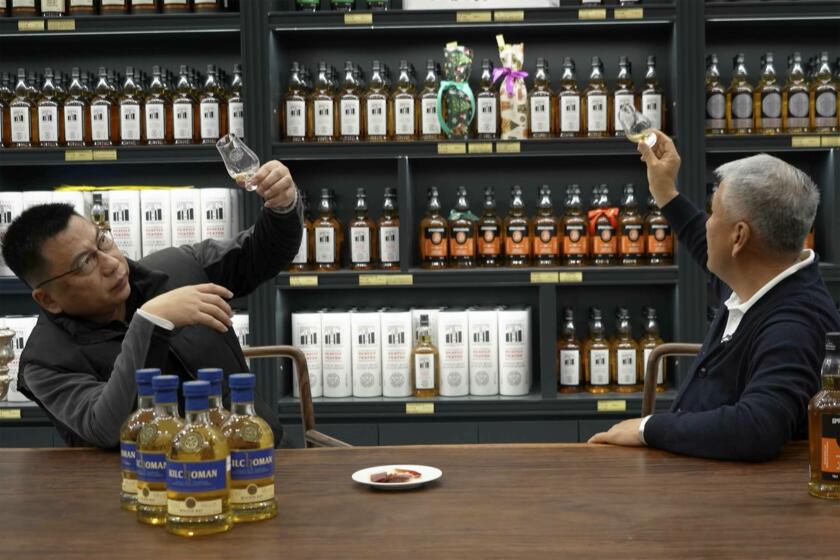 En esta imagen tomada de un video, Raymond Lee, (derecha) fundador del Single Malt Club de China, hace una cata de whisky en una tienda de Beijing, el 9 de diciembre de 2023. (AP Foto/Caroline Chen)