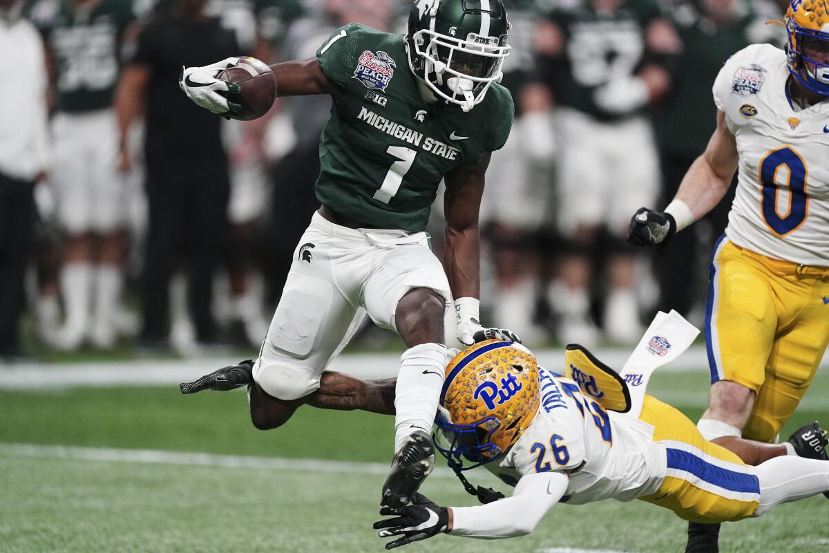 FILE - Michigan State wide receiver Jayden Reed (1) leaps near Pittsburgh defensive back Judson Tallandier (26) during the first half of the Peach Bowl NCAA college football game Dec. 30, 2021, in Atlanta. Reed, an AP All-Big Ten all-purpose player, returned two punts for touchdowns last season and had team highs in catches (59), yards receiving (1,026) and receiving touchdowns (10). (AP Photo/John Bazemore, File)