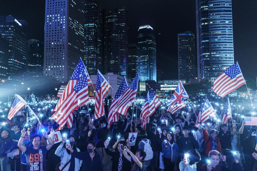 HONG KONG, CHINA -- THURSDAY, NOVEMBER 28, 2019: Singing the "star spangle banner," waving American flags and waving banners bearing the protest slogan: “Liberate Hong Kong, revolution of our times,” Pro-democracy demonstrators gather for a Thanksgiving rally to commemorate President Trump signing the Hong Kong Human Rights and Democracy Act into law, at the Central district of Hong Kong, on Nov. 28, 2019. The Hong Kong Human Rights and Democracy Act requires an annual review of whether Hong Kong retains enough autonomy to justify its special trade status with the U.S. The semi-autonomous Chinese territory has separate legal and economic systems as a result of its history as a British colony.(Marcus Yam / Los Angeles Times)