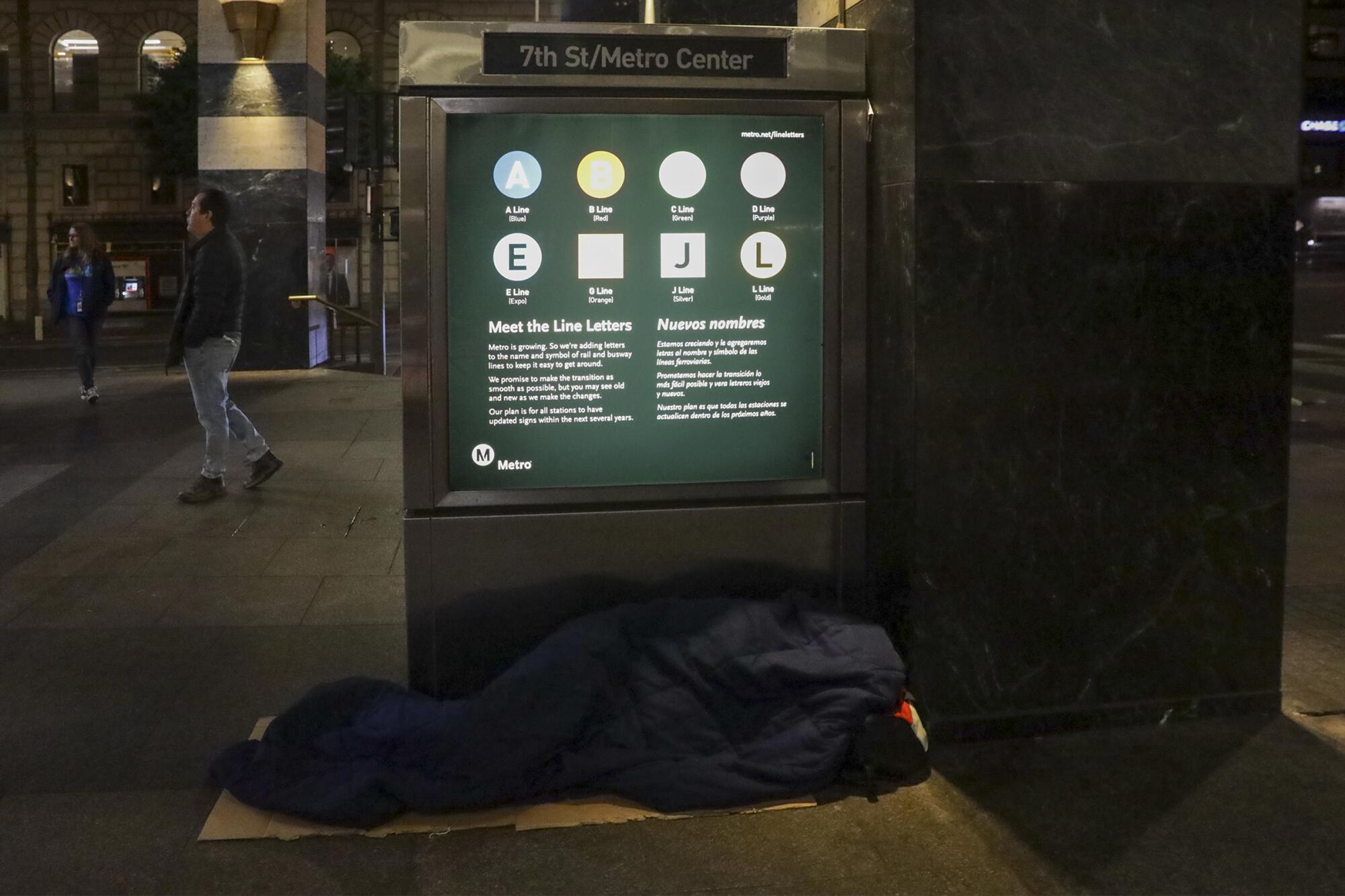 A homeless person sleeps in front of the closed gates of 7th Street Metro station 