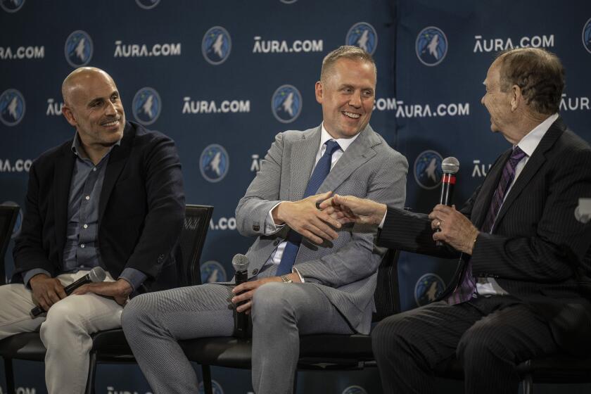 FILE - Marc Lore, left looks on as the Minnesota Timberwolves' new president of basketball operations, Tim Connelly, shakes hands with team owner Glen Taylor, right, in Minneapolis on May 31, 2022. Connelly made his first trade for the Timberwolves after about six weeks on the job, a bold move to get Rudy Gobert that was as risky as it was unconventional. Going big has been no small part of this breakthrough season — and dominant start to the playoffs — for the surging Timberwolves. (Jerry Holt/Star Tribune via AP, File)
