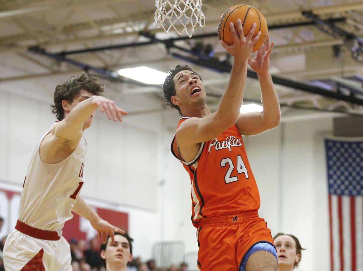 Pacifica Christian's Alex Stewart (24) flies through the key for a reverse lay-up against Orange Lutheran.