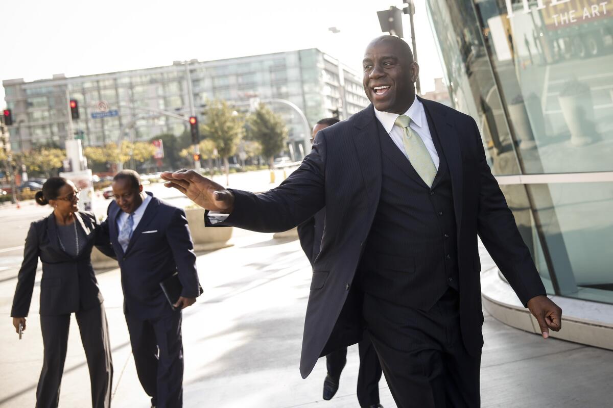 Magic Johnson waves to fans while walking to a news conference Wednesday to announce the purchase of the L.A. Sparks by the investment group led by Johnson and Mark Walter, controlling owner of the Dodgers.