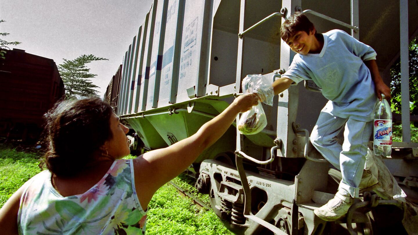 Denis gets food and water from Marta Hernandez de la Cruz, a rail-side resident of Mapastepec, Mexico.