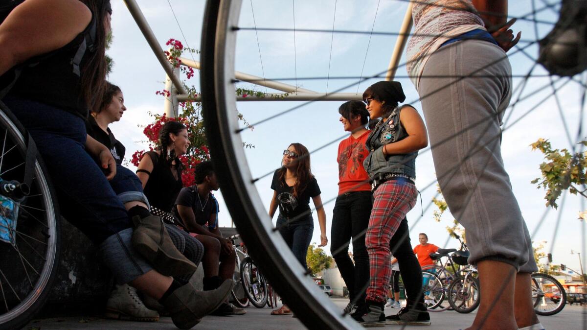 Female bike riders, along with a few members of the Ovarian Psycos, talk with one another before their evening ride.