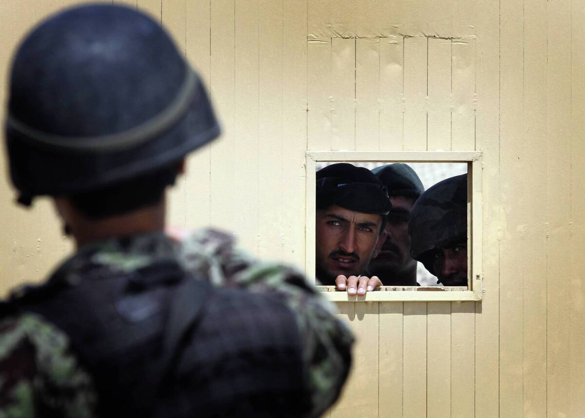 Afghan soldiers look through the security hole of one of the gates at the Kabul airport after a deadly shooting rampage in April 2011.