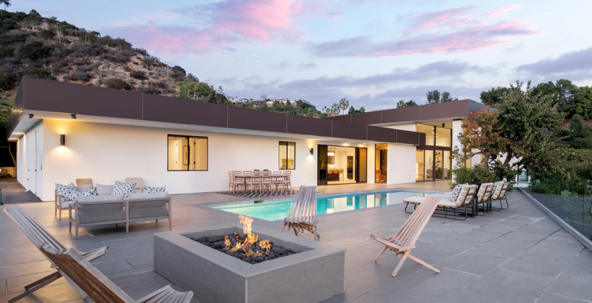 The back of a house with a fire pit and swimming pool.
