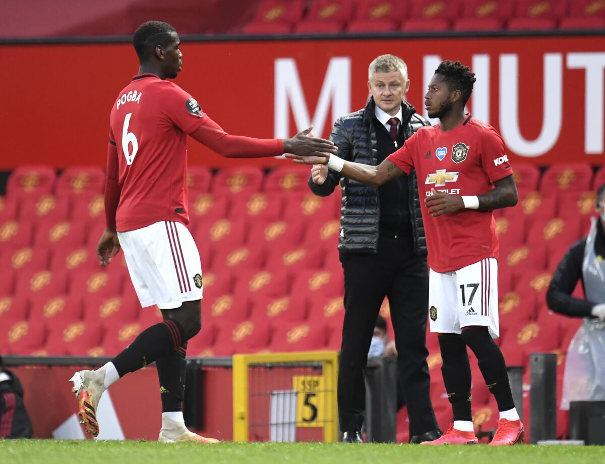Manchester United's Paul Pogba, left, gestures to teammate Fred as he is substituted during the English Premier League soccer match between Manchester United and Southampton at Old Trafford in Manchester, England, Monday, July 13, 2020. (AP Photo/Dave Thompson,Pool)