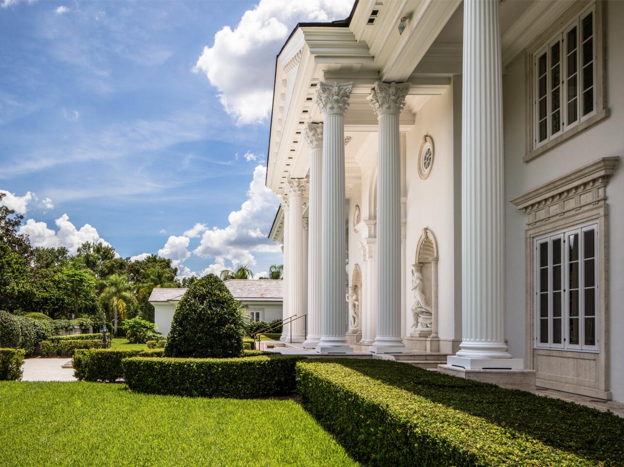 White columns, statues and sculpted hedges at the front entrance.