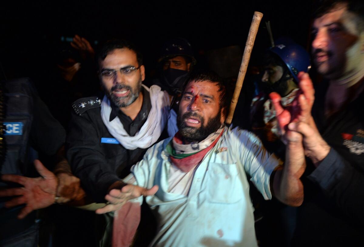 Pakistani police arrest an injured supporter of Canadian cleric Tahirul Qadri following clashes near the prime minister's residence in Islamabad on Sunday.