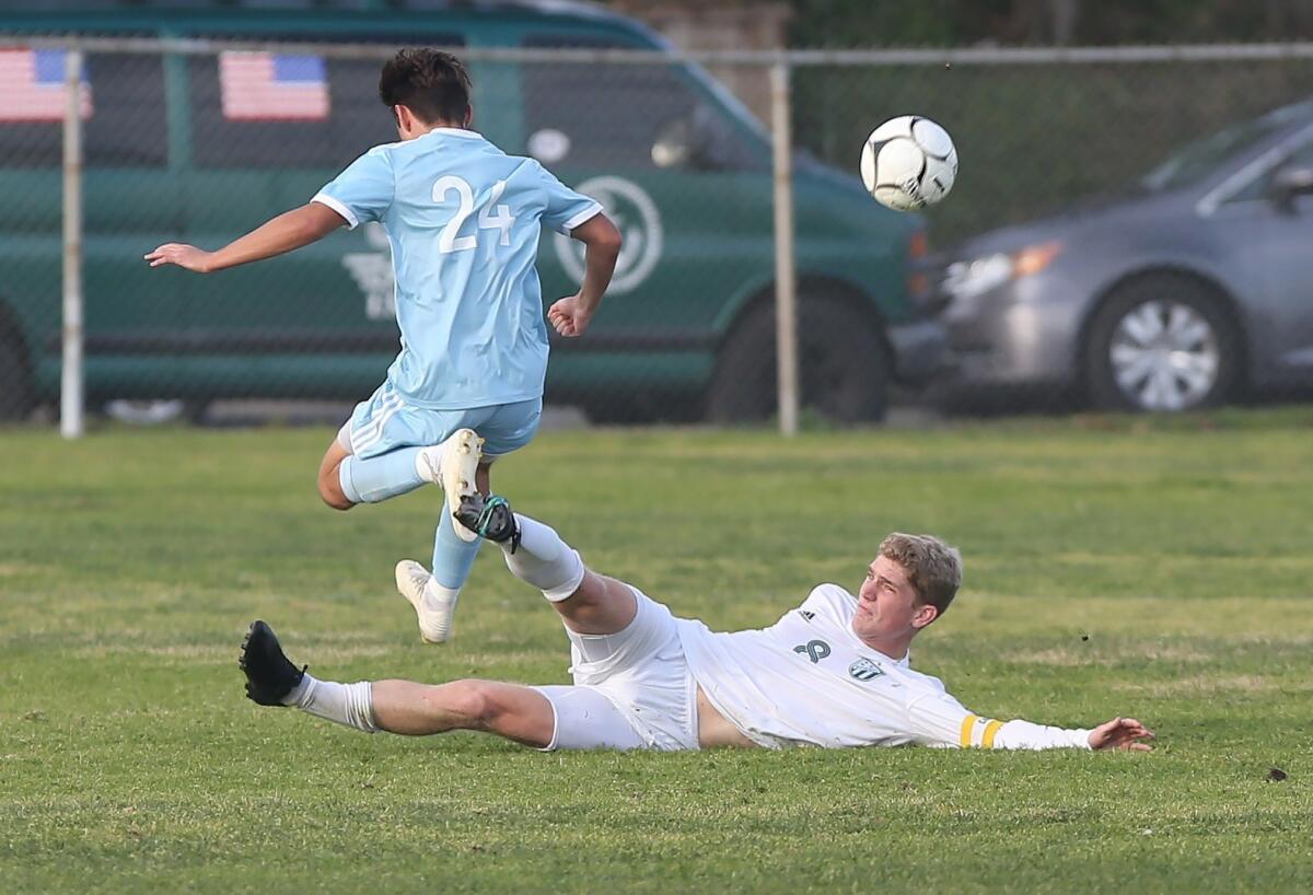 Edison's Wyatt Burris slides in to disrupt a shot on goal from Corona del Mar's Taylor Demarais in a Surf League match in Newport Beach on Jan. 11.