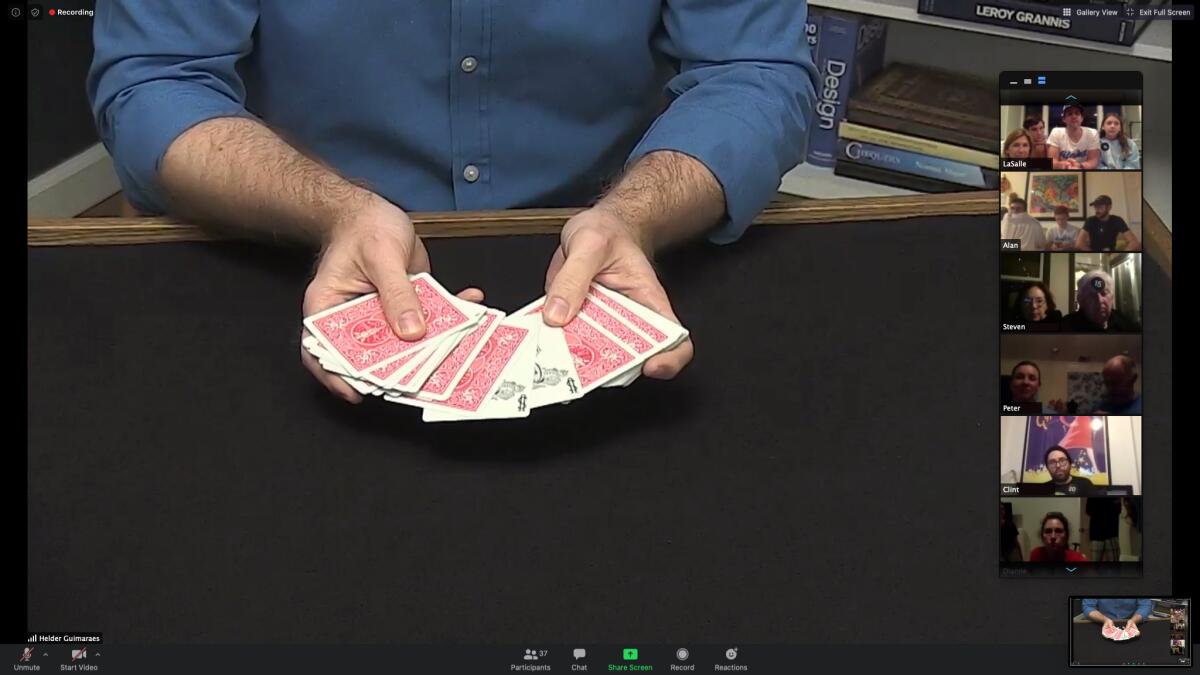 A screengrab from Zoom shows Helder Guimarães performing a magic trick online